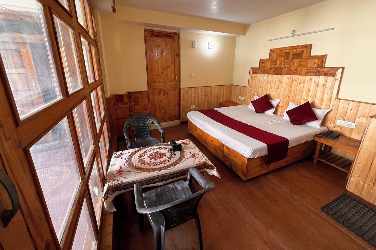 Un dormitorio con paneles de madera, una cama, un escritorio y una silla.