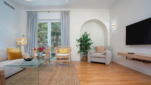 A modern living room with a glass coffee table, a sofa, a chair, a TV, and a large window with curtains. - Exclusive Apartment 5BD in Seville. Carlos V (Seville)