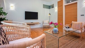 A modern living room with wicker furniture, a glass coffee table, and a flat-screen TV mounted on the wall. - Exclusive Apartment 5BD in Seville. Carlos V (Seville)