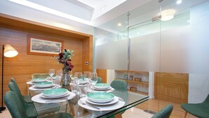 A modern dining area with a glass table set for six, surrounded by green upholstered chairs. - Exclusive Apartment 5BD in Seville. Carlos V (Seville)