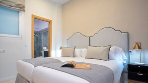 A double bed with a grey and white duvet, a bedside table with a lamp, and a window with a curtain. - Exclusive Apartment 5BD in Seville. Carlos V (Seville)