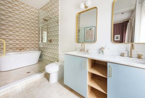 A modern bathroom with a freestanding bathtub, a toilet, and a vanity with a sink and mirror. - Chic 4bd Downtown Home w/ Rooftop (Charleston)