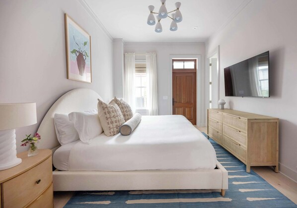 A bedroom with a bed, bedside table, dresser, and a TV.