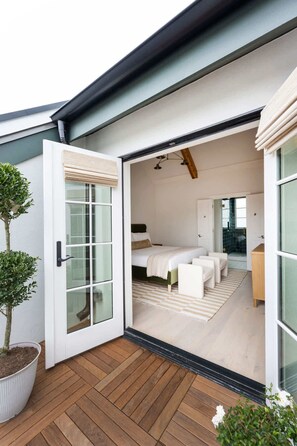 A modern bedroom with a large sliding glass door leading to a bathroom.