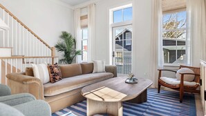 Un salon avec un canapé beige, une table basse en bois, un fauteuil et un escalier.