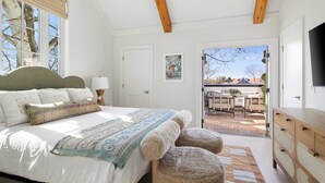 Une chambre avec un grand lit, une commode en bois et une vue sur la terrasse extérieure.