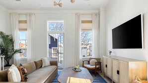 Un salon avec un canapé, une table basse et un téléviseur fixé au mur.