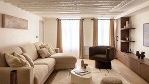 A modern living room with a beige sofa, a dark armchair, and a coffee table.