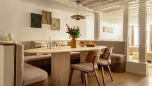 A dining area with a round table, cushioned seating, and a vase with flowers.
