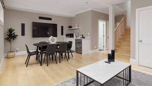 A modern living room with a dining area, a kitchen, and a staircase.