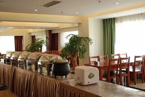 Ein reichhaltiges Buffet mit langer Theke, mehreren Speisenstationen und einem Essbereich mit Stühlen und Tischen.