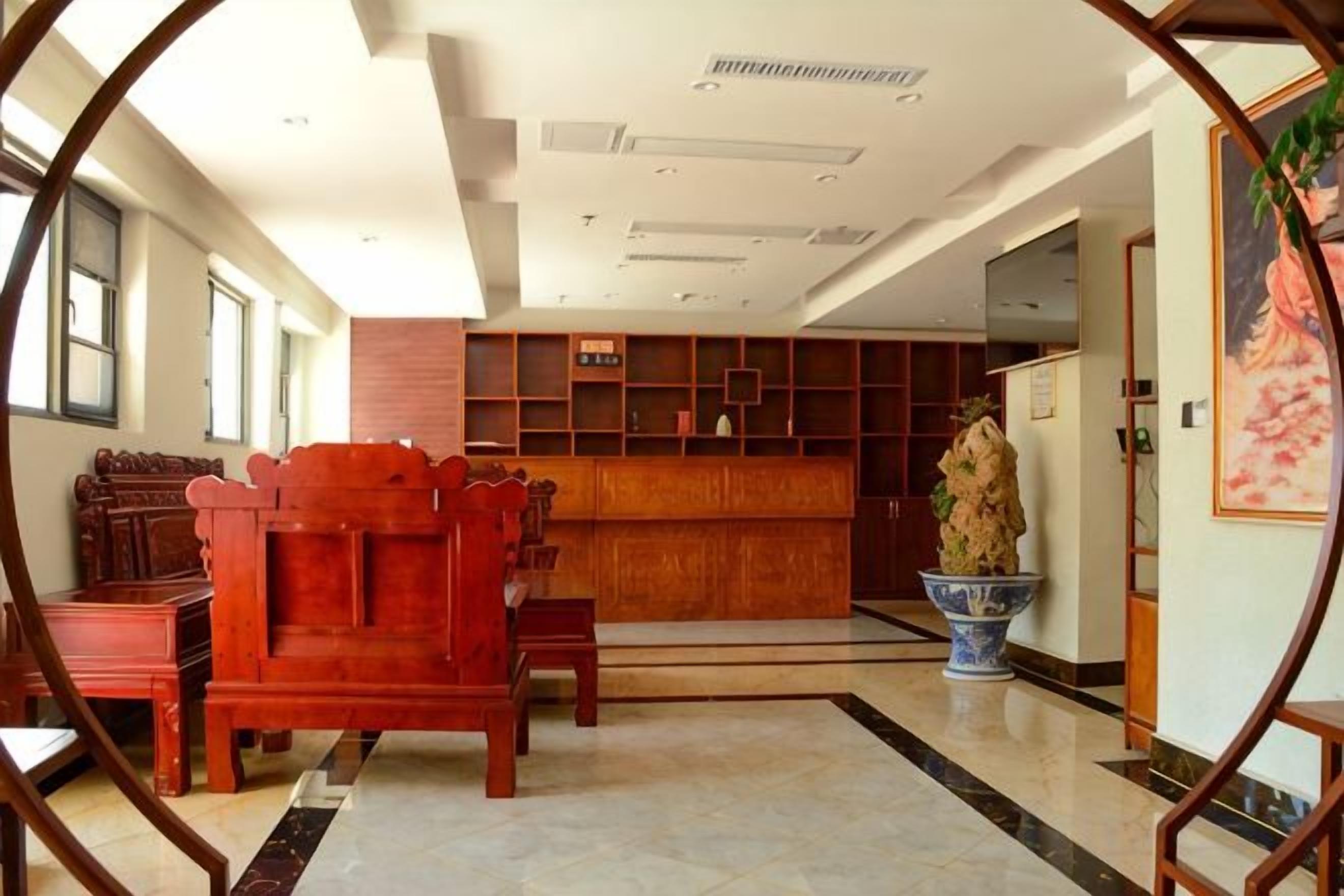 A hotel lobby with a reception desk, seating area, and a large vase.