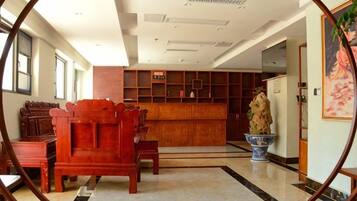 A hotel lobby with a reception desk, seating area, and a large vase.