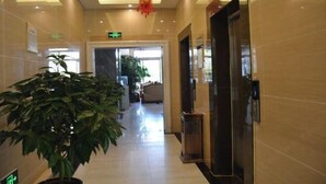 Un vestíbulo de hotel con una planta grande en maceta, un mostrador de recepción y un ascensor.