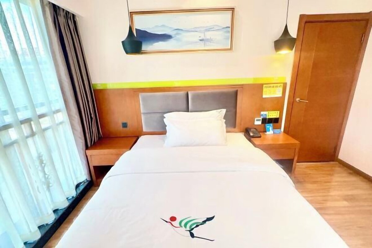 Una habitación de hotel con una cama, una mesita de noche, un cuadro en la pared y una puerta.