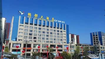 A multi-story hotel with a prominent sign, surrounded by other buildings and a clear sky.