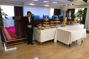 Disposición de buffet con diferentes alimentos y una persona a un lado.