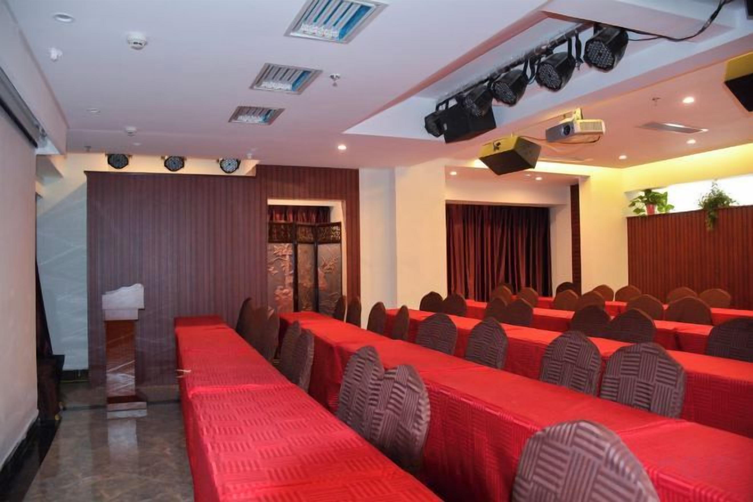 A conference room with rows of tables, chairs, and a stage with a projector.