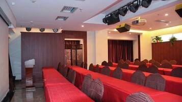 A conference room with rows of tables, chairs, and a stage with a projector.
