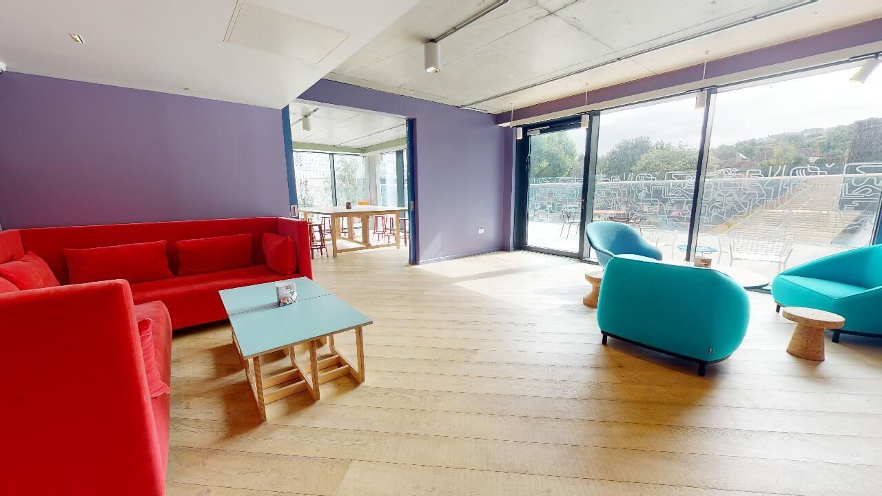 A modern living room with a red sofa, teal armchairs, and a wooden coffee table.