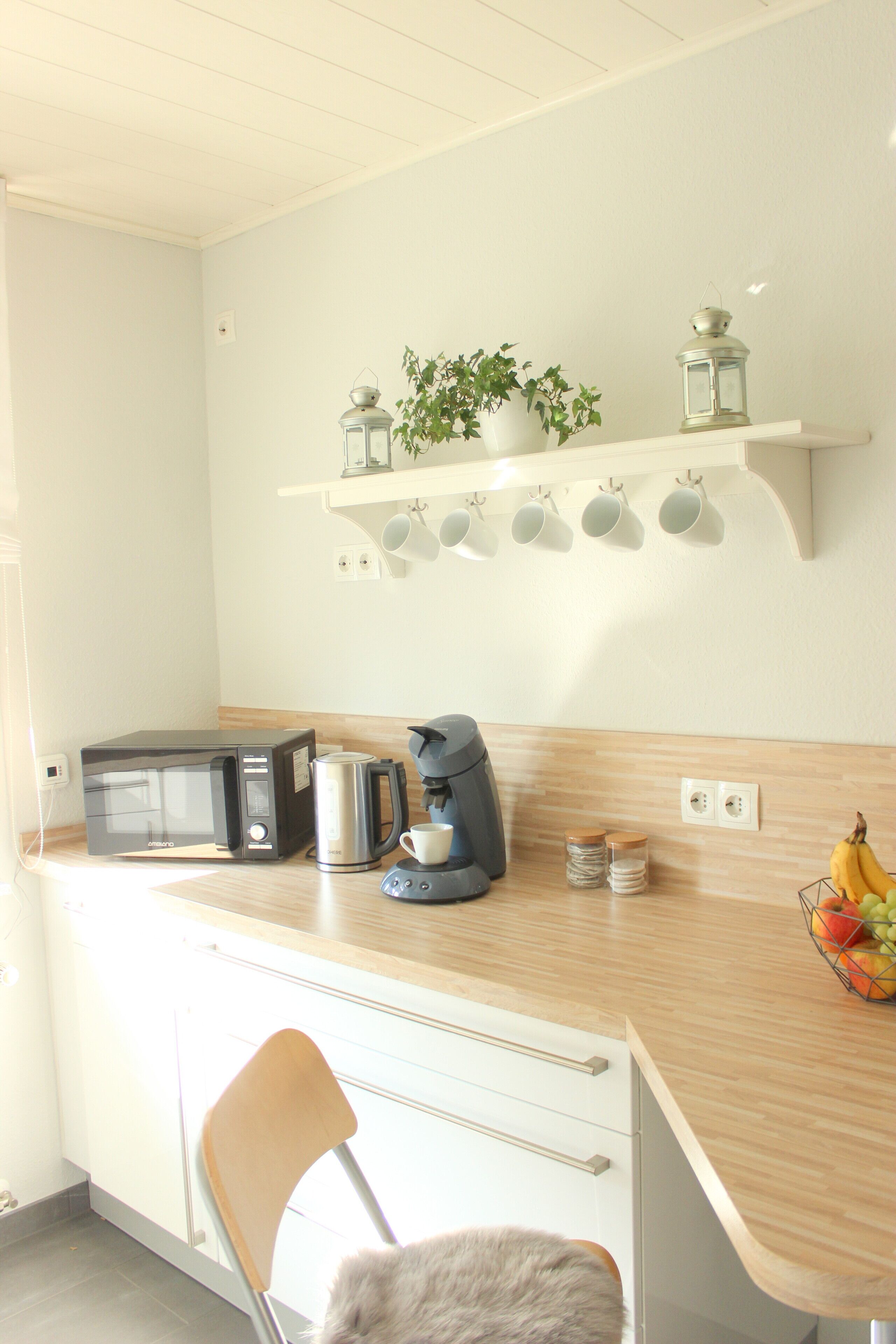 A kitchen with a microwave, coffee maker, and a fruit basket on the counter.