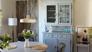 Un coin repas comprenant une table ronde, des chaises, un vase avec des fleurs et un meuble avec des portes en verre.