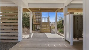 Eine Holzterrasse, die zu einem überdachten Außenbereich mit einer Treppe führt.