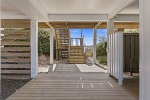 A wooden deck leading to a covered outdoor area with a staircase.