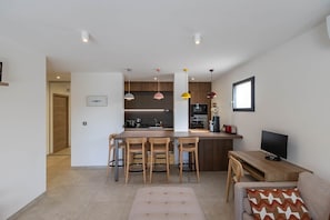 Cozinha moderna com ilha central, banquetas e iluminação pendente.