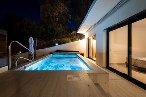 A modern outdoor swimming pool with a glass enclosure, a wooden deck, and a sliding glass door leading to a bedroom. - Festive Holidays 🎄🥂 Villa Heated Pool 28°C (Pietrosella)