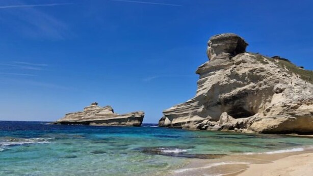 A beach with clear turquoise water and a rocky formation. - 70m2 house with large terrace in secure residence with swimming pool. (Bonifacio)