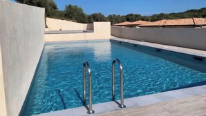 A rectangular swimming pool with clear blue water, surrounded by a light-colored deck. - 70m2 house with large terrace in secure residence with swimming pool. (Bonifacio)