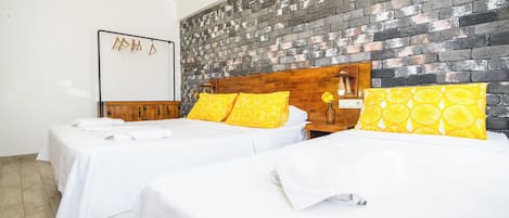 A hotel room with two beds, white bedding, and a brick-patterned headboard.