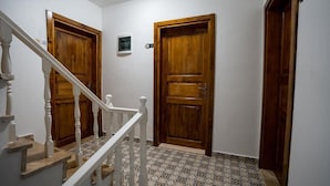 A hallway with two wooden doors, a staircase with white balusters, and patterned floor tiles.