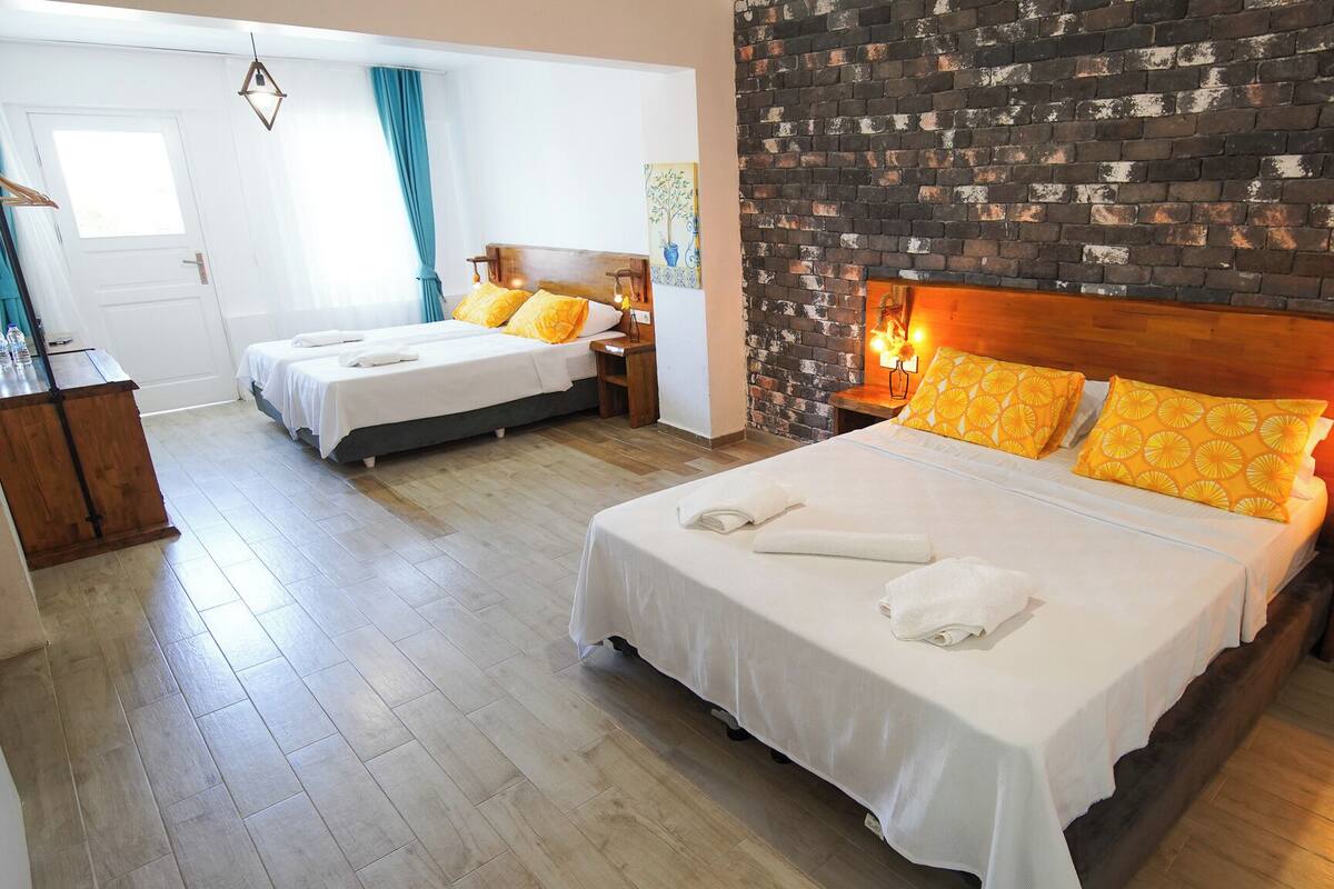 Habitación de hotel con dos camas, una pared de ladrillo y un cabecero de madera.