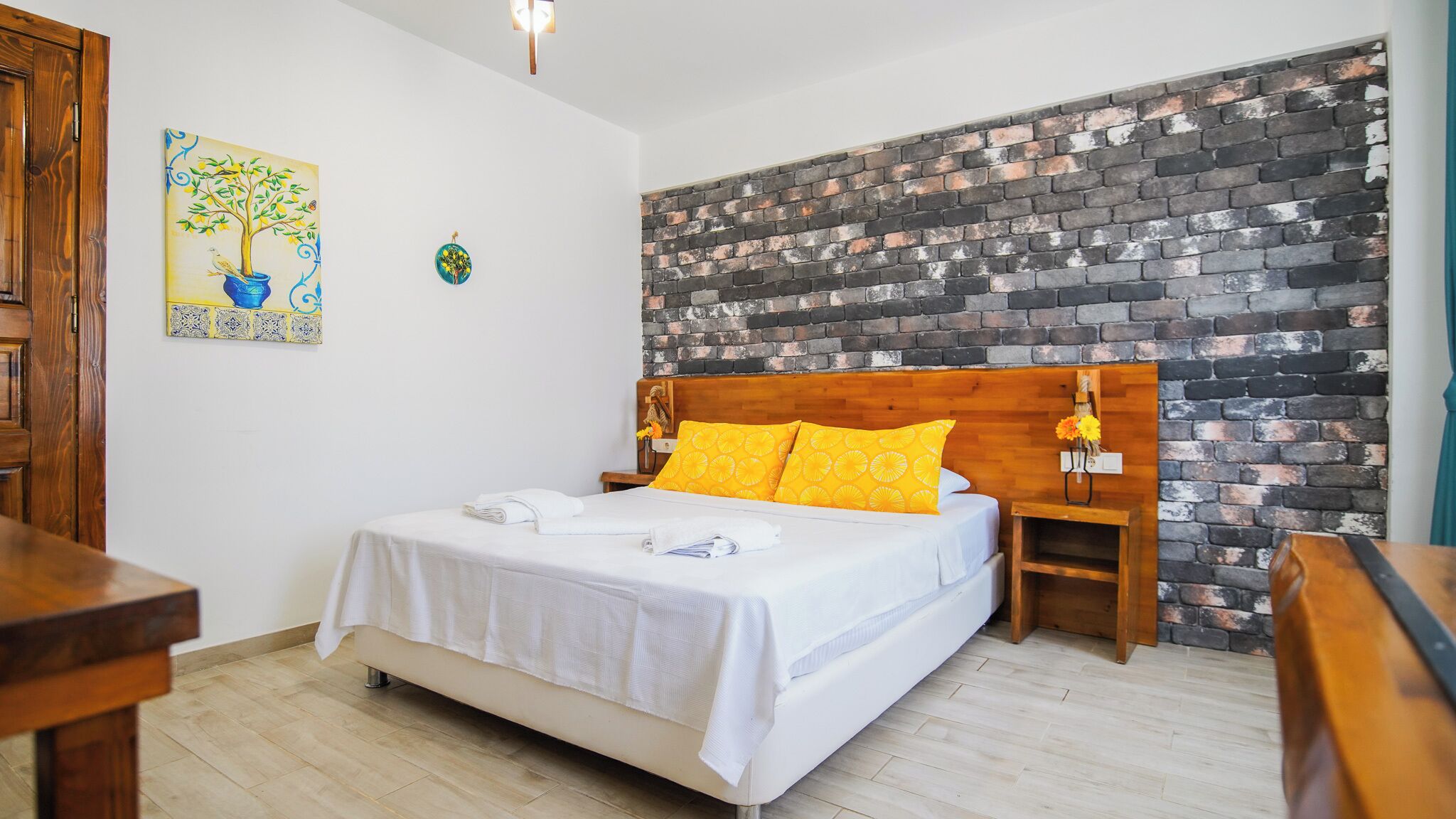 A bedroom with a bed, wooden headboard, and a brick-patterned wall.