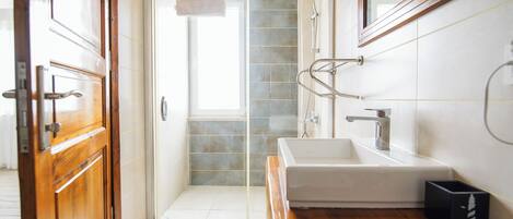 A modern bathroom with a glass shower door, a white sink, and a wooden vanity.