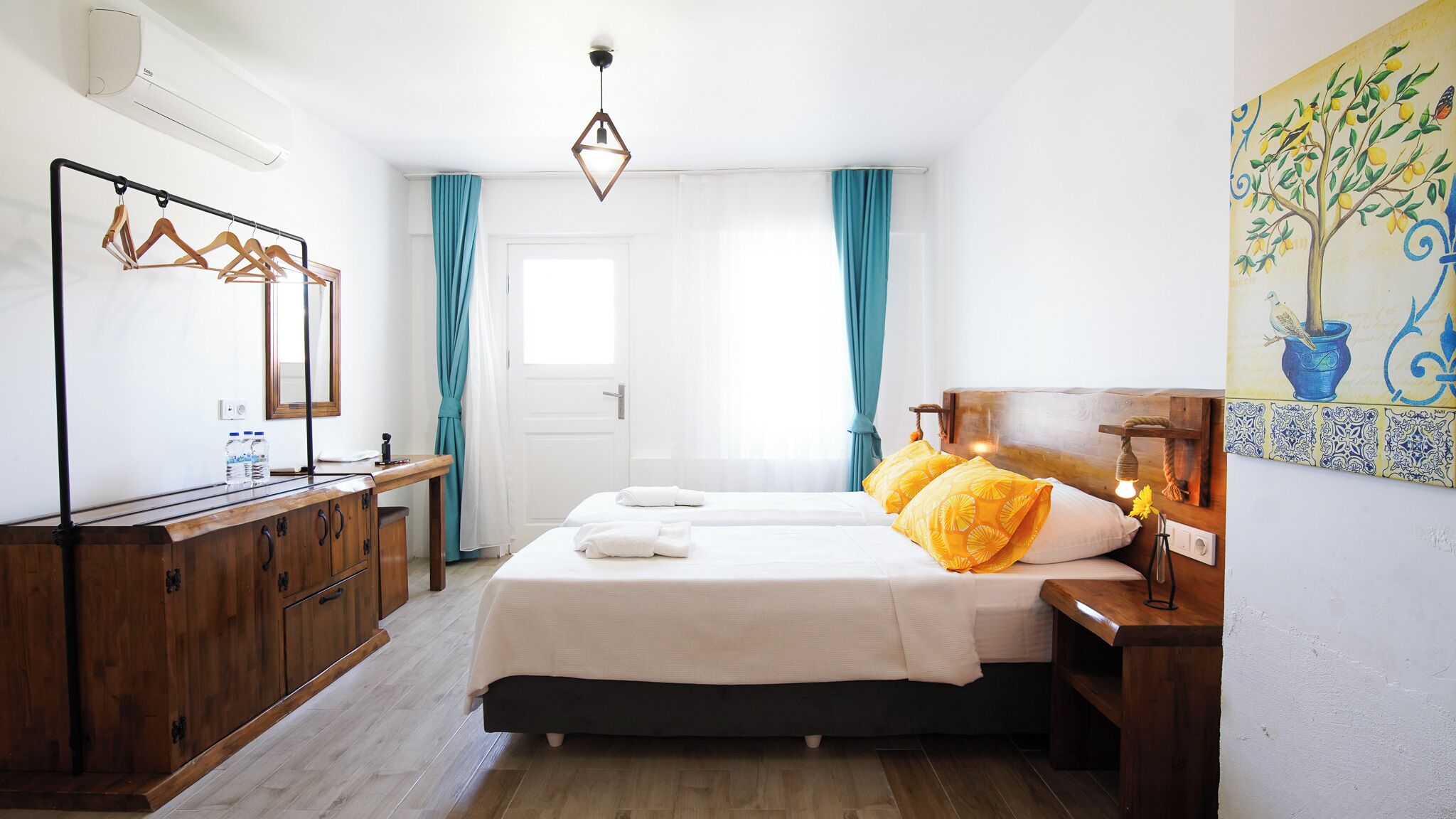 Une chambre d’hôtel avec un lit, une commode en bois, un miroir et un tableau au mur.