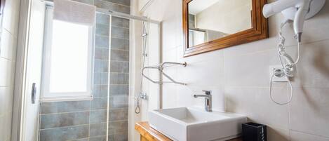 A modern bathroom with a shower, a sink, and a hairdryer mounted on the wall.