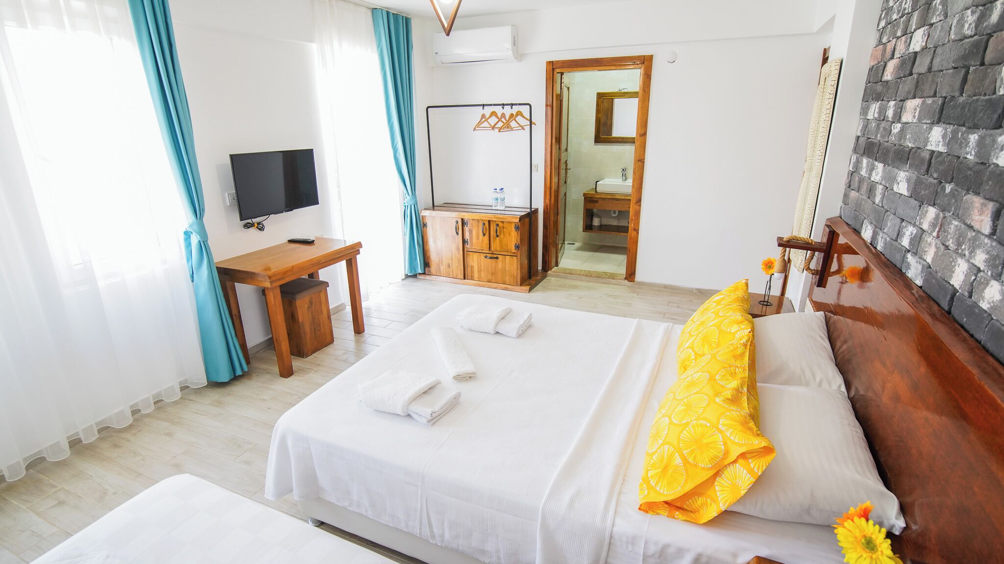 A hotel room with two beds, a desk, a TV, and a bathroom visible through an open door.