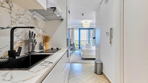 A modern hotel room with a marble backsplash, a black sink, and a view of the city through large windows. - bnbme - Gold Crest Views 2 - STUDIO (Dubai)
