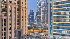 A high-rise hotel with multiple floors, a parking area, and a view of the cityscape. - bnbme - Gold Crest Views 2 - STUDIO (Dubai)