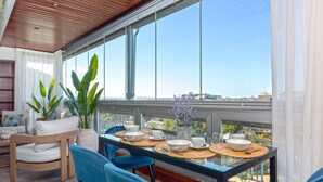 A dining area with a glass table, blue chairs, and a view of the city through large windows. - Bright Stay Córdoba. Paseo de la Victoria (Córdoba)