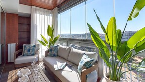 A balcony with a sofa, two potted plants, a glass table, and a view of the city. - Bright Stay Córdoba. Paseo de la Victoria (Córdoba)