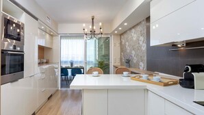 A modern kitchen with white cabinets, a built-in oven, and a central island with two white cups. - Bright Stay Córdoba. Paseo de la Victoria (Córdoba)
