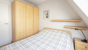 A bedroom with a bed, wooden wardrobe, bedside table, and a picture on the wall. - Knokke Beach Hideaway (Knokke-Heist)