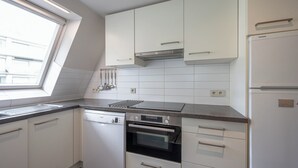 A modern kitchen with white cabinetry, a built-in oven, and a window providing natural light. - Knokke Beach Hideaway (Knokke-Heist)