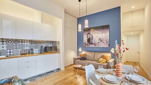 A modern kitchen with white cabinets, a patterned backsplash, and a dining area with a table set for two. - Superb Apartement Center of Paris Le Marais (Paris)