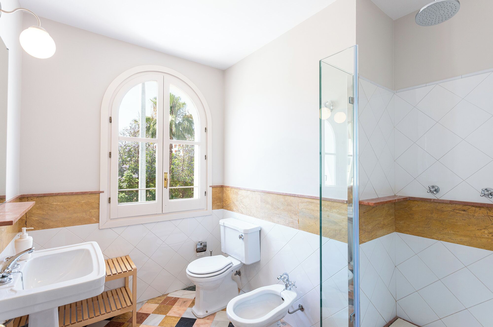 A bathroom with a sink, toilet, bidet, and a glass shower enclosure.