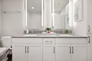 A modern bathroom with two sinks, a toilet, and a large mirror. - MCK211 | McKinney Corporate 2BD | Pool | Workspace (McKinney)